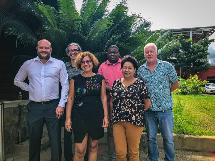 Groupe de 6 personnes posant souriantes devant un jardin