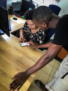 Jeune homme montrant un document via smartphone à une dame assise