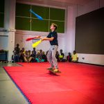 Jeune homme jonglant sur une planche tenu par un cylindre 