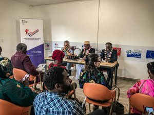 Trois homme assis à une table en ligne 