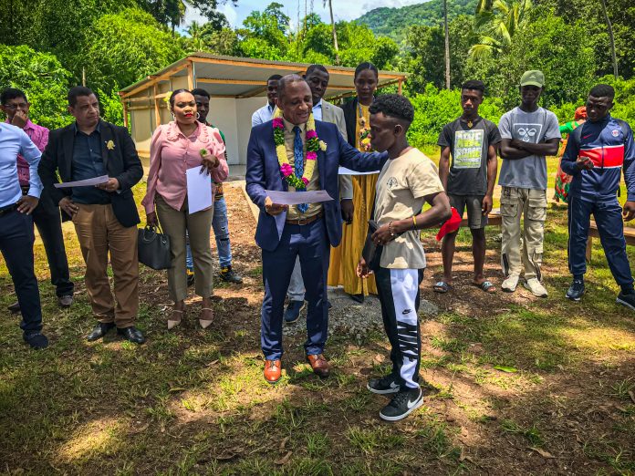 Un jeune homme se voit remettre un diplôme en la présence de personnes qui semblent officielles