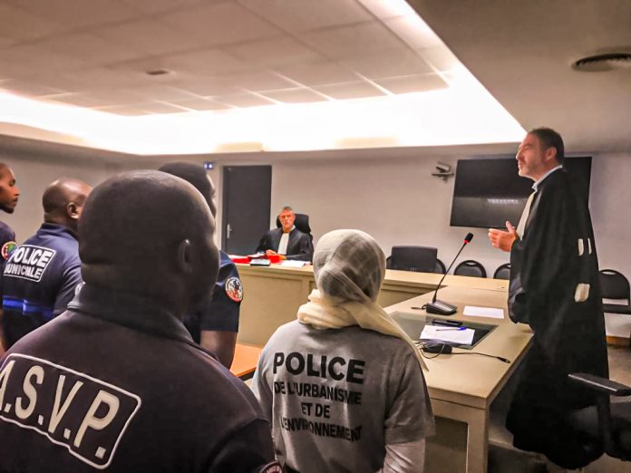 Des personnes des forces de l'ordre municipales sont vues de dos et font face à des jurés dans un tribunal